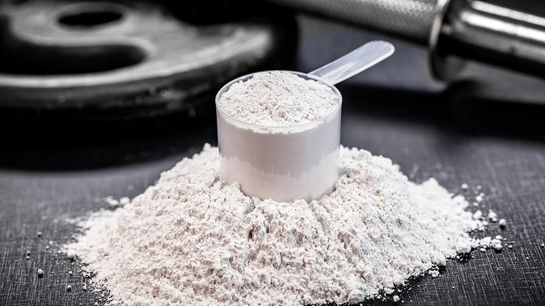 Neutral creatine powder, scoop and water glass on a clean bench for a Healthy.co.nz NZ buying guide.