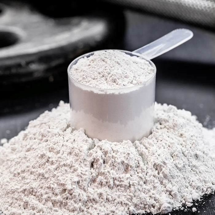 Neutral creatine powder, scoop and water glass on a clean bench for a Healthy.co.nz NZ buying guide.