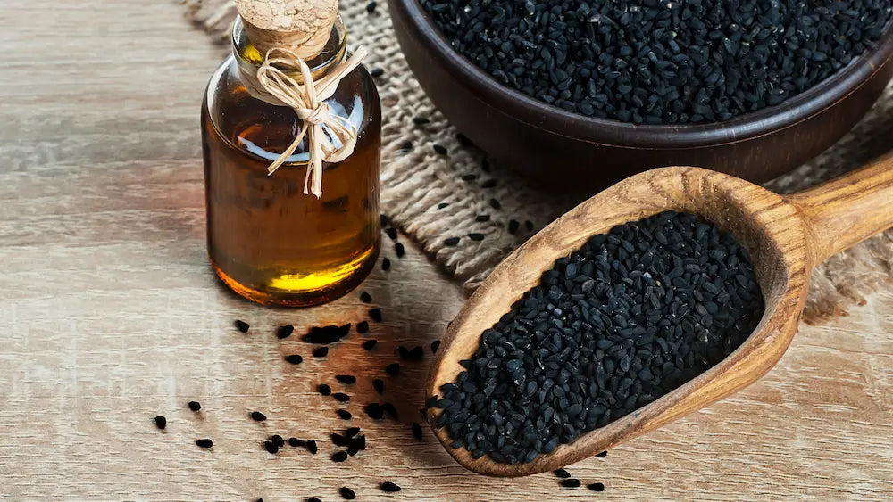 Black seed oil liquid bottle, measured teaspoon, softgels and Nigella sativa seeds compared for serving size, freshness and TQ labels