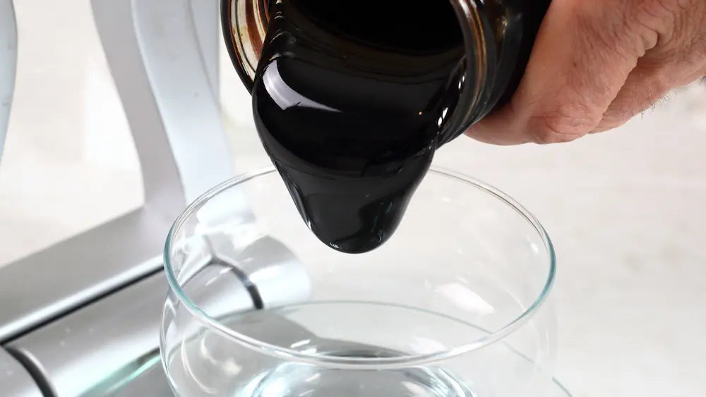 Blackstrap molasses and black treacle in separate glass bowls on a New Zealand kitchen bench with baking ingredients