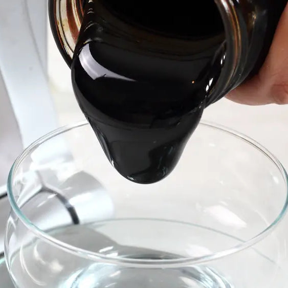 Blackstrap molasses and black treacle in separate glass bowls on a New Zealand kitchen bench with baking ingredients
