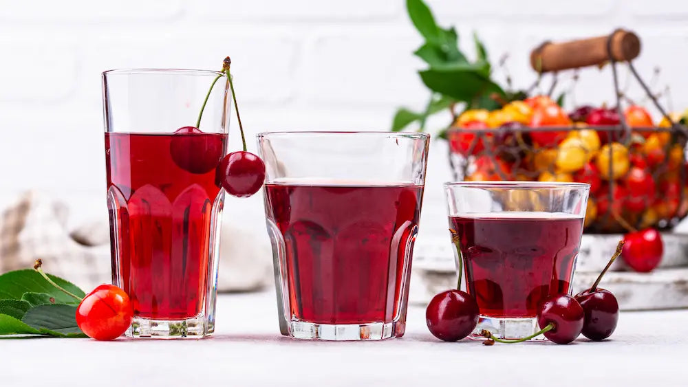 Tart cherry concentrate and a diluted cherry drink in an evening kitchen beside an open fridge