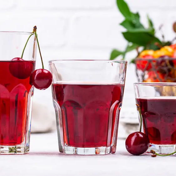 Tart cherry concentrate and a diluted cherry drink in an evening kitchen beside an open fridge