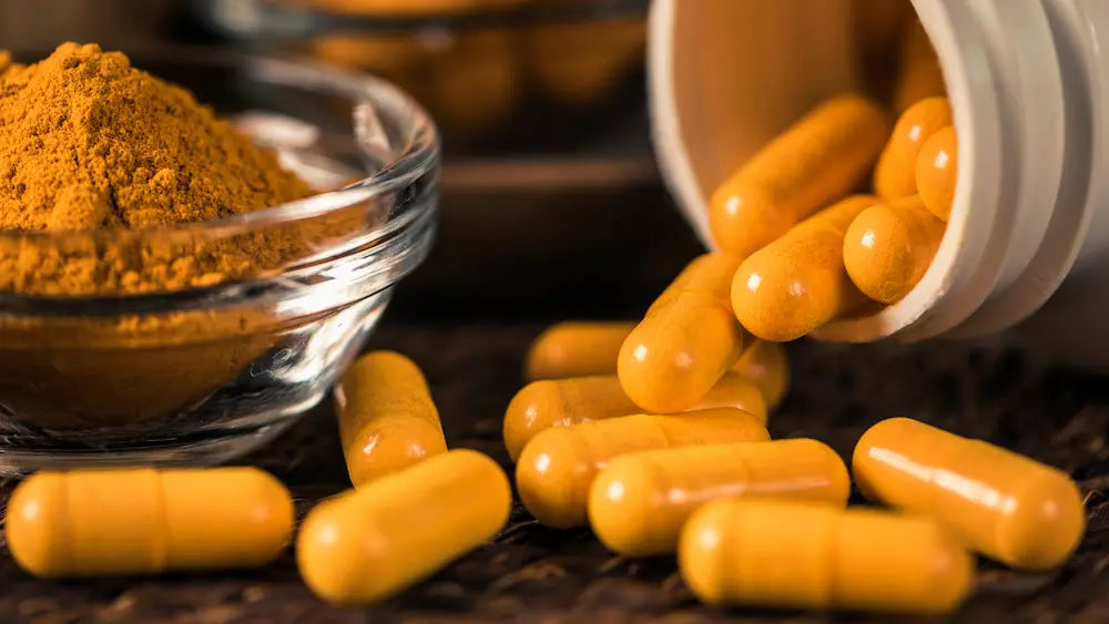 Turmeric capsules and oral spray beside turmeric root in a clean Healthy NZ wellness setting