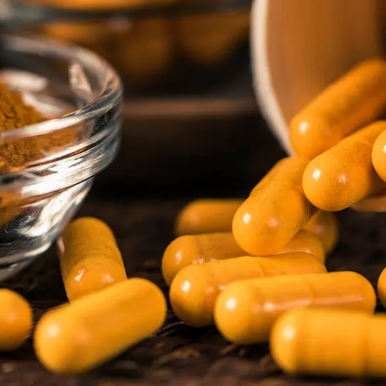 Turmeric capsules and oral spray beside turmeric root in a clean Healthy NZ wellness setting