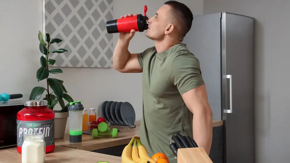 Protein powder beside a shaker, breakfast smoothie and bowl of oats in a bright New Zealand kitchen