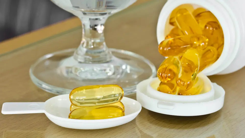 Cod liver oil liquid and softgels beside vitamin A and vitamin D supplement containers on a clean natural-health counter