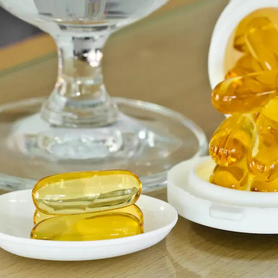 Cod liver oil liquid and softgels beside vitamin A and vitamin D supplement containers on a clean natural-health counter