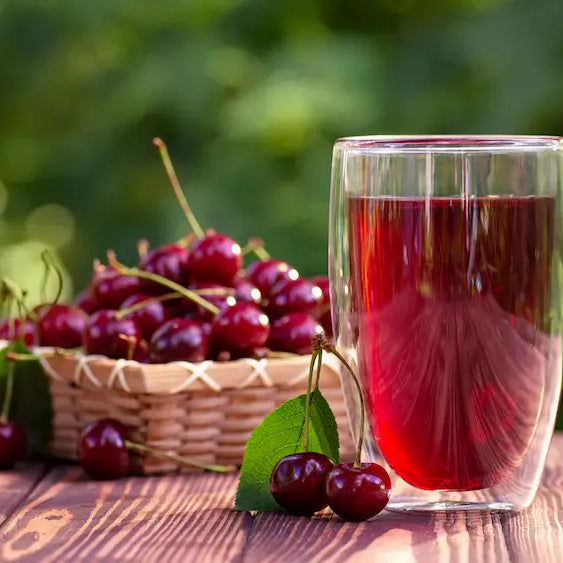 Dark ruby tart cherry concentrate with fresh tart cherries and a cherry product bottle showing an ingredient-focused label