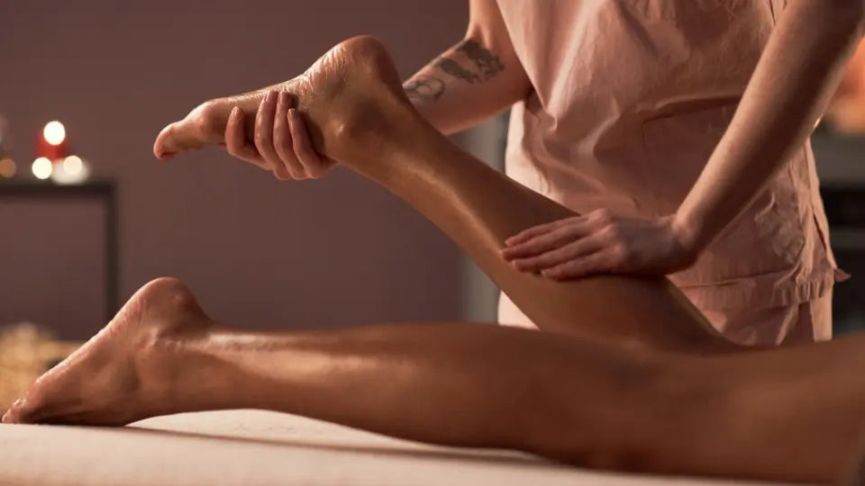 Adult preparing an emu oil massage with a pure oil bottle and balm-style warming rub nearby