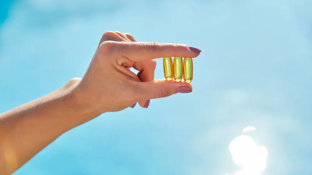 Three fish oil with vitamin D supplement bottles and softgels in a clean natural wellness setting.