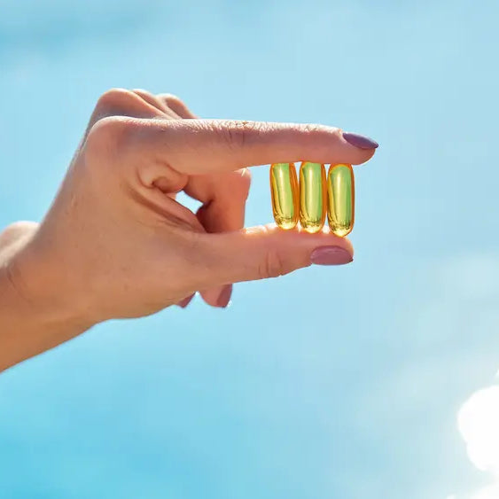 Three fish oil with vitamin D supplement bottles and softgels in a clean natural wellness setting.