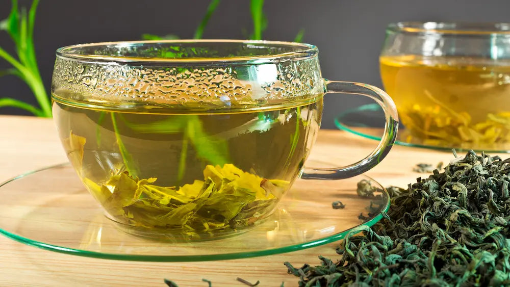 Brewed green tea, tea leaves and a green tea extract capsule arranged along a morning to afternoon routine