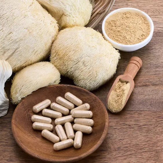 Lion's Mane mushroom with ginkgo leaves, brahmi foliage, black pepper and vegetable capsules beside a supplement bottle.
