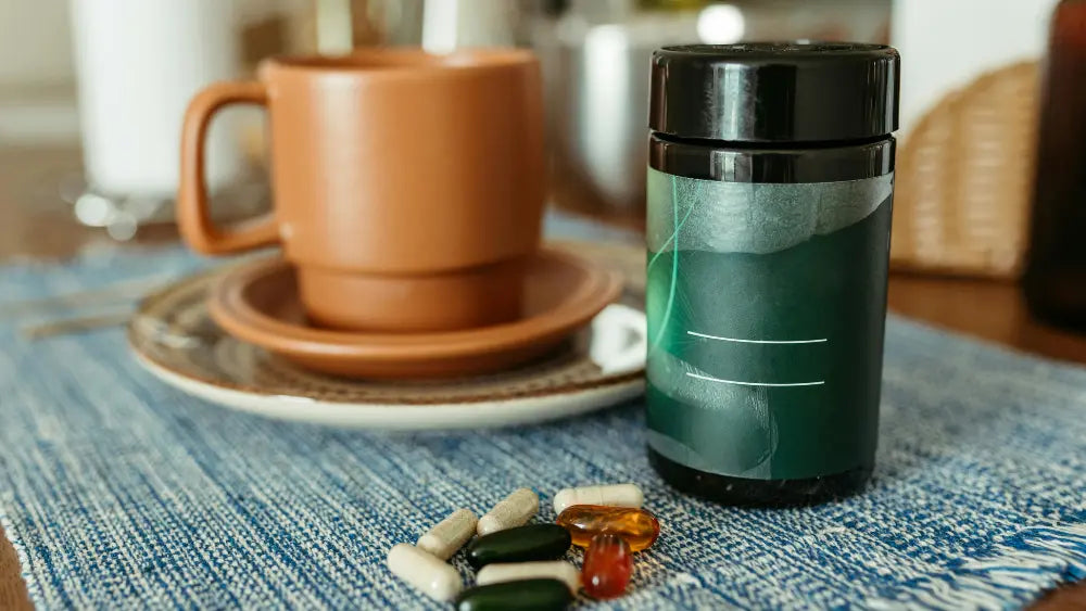 Liquid L-carnitine bottle with a measuring spoon beside a bottle of acetyl-L-carnitine capsules on a neutral surface.