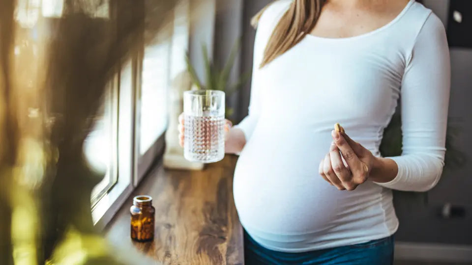 Pregnancy supplement bottles beside a handwritten prenatal vitamin label audit on a bright kitchen bench